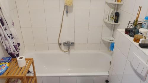 uma banheira branca com uma cabeça de chuveiro na casa de banho em Privatzimmer in St. Jürgen, gute Anbindung Zentral em Lübeck
