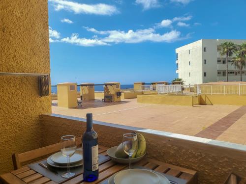 a bottle of wine and glasses on a table on a balcony at Nena Luxury Home by HelloApartments in Puerto de Santiago