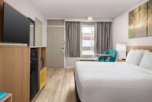 a hotel room with a bed and a flat screen tv at Days Inn by Wyndham Lake City I-75 in Lake City
