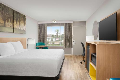 a hotel room with a bed and a flat screen tv at Days Inn by Wyndham Lake City I-75 in Lake City