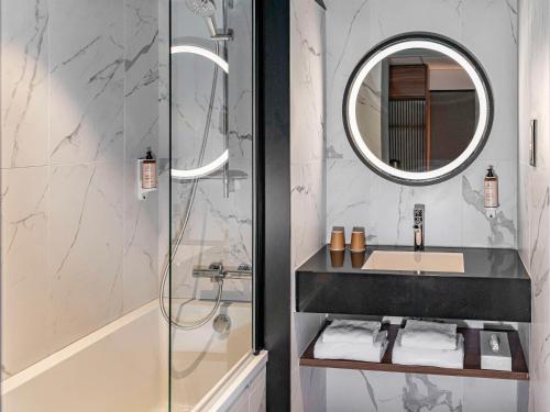 een badkamer met een wastafel en een douche met een spiegel bij Mercure Caen Centre Port De Plaisance in Caen