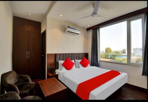 Schlafzimmer mit einem Bett mit roten Kissen und einem Fenster in der Unterkunft Hotel Maharaja in Udaipur