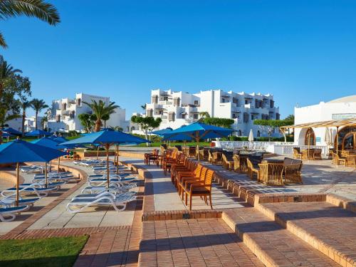 a row of tables and chairs with blue umbrellas at Mercure Hurghada Hotel in Hurghada