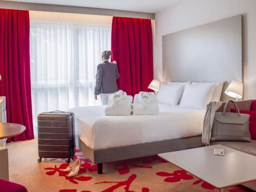 uma mulher num quarto de hotel com uma cama grande em Mercure Tours Nord em Tours