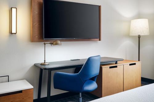 a desk with a blue chair and a tv at Fairfield Inn & Suites Auburn Opelika in Opelika