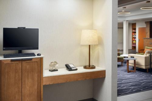 a room with a desk with a television and a lamp at Fairfield Inn & Suites Auburn Opelika in Opelika