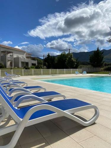 une rangée de chaises longues à côté d'une piscine dans l'établissement Saint-Florent Appartement duplex, à Oletta
