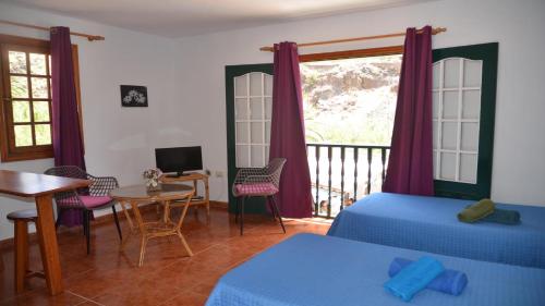 a room with two beds and a table and a balcony at Apartamento Nelly S4 in Valle Gran Rey
