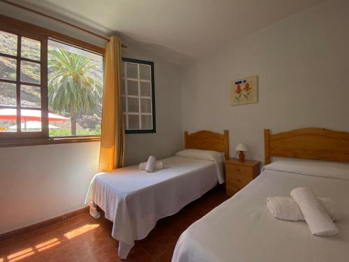 a bedroom with two beds and a window with a palm tree at Apartamento Nelly S2 in Valle Gran Rey