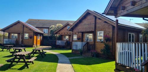 a log cabin with picnic tables in a yard at Bacchus Hotel Log Cabins in Sutton on Sea