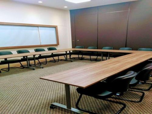 a conference room with tables and chairs and a whiteboard at ibis budget Nao Me Toque in Não Me Toques