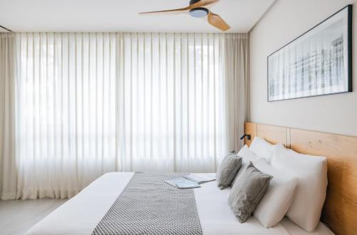 a bedroom with a white bed with a ceiling fan at The Arbel Tel Aviv in Tel Aviv