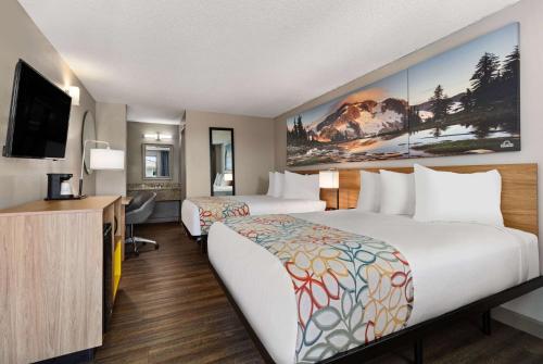 a hotel room with two beds and a flat screen tv at Days Inn by Wyndham Lakewood South Tacoma in Lakewood