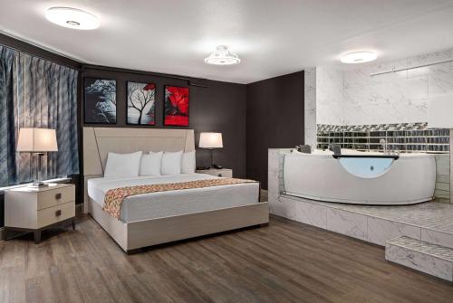 a bedroom with a large bed and a bath tub at Days Inn by Wyndham Lakewood South Tacoma in Lakewood