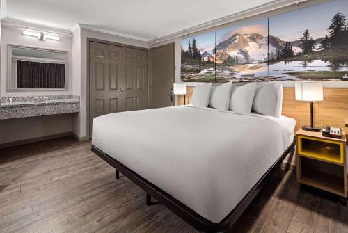 a hotel room with a bed and a painting on the wall at Days Inn by Wyndham Lakewood South Tacoma in Lakewood