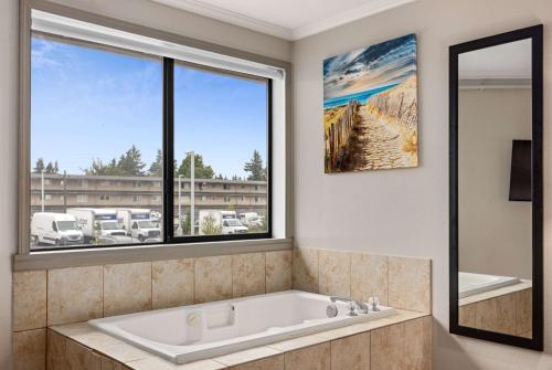 a bath tub in a bathroom with a large window at Days Inn by Wyndham Lakewood South Tacoma in Lakewood
