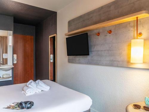 een kamer met een bed en een tv aan de muur bij ibis budget Paris Porte de Pantin in Pantin