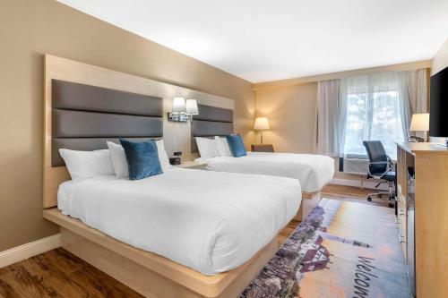 a hotel room with two beds and a desk at Casco Bay Hotel, Ascend Hotel Collection in South Portland
