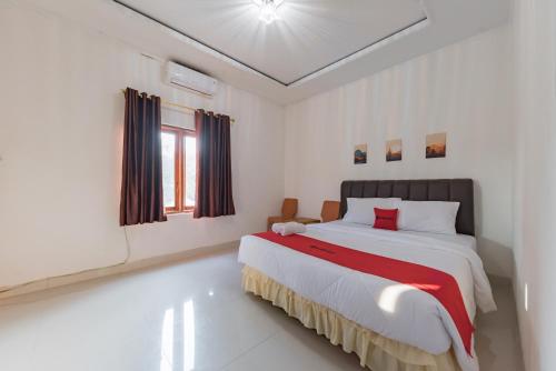 a white bedroom with a large bed with red accents at RedDoorz near Ciletuh Sukabumi in Cilowa