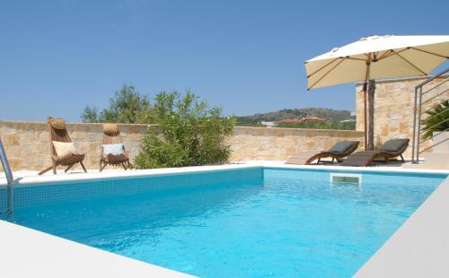 a swimming pool with two chairs and an umbrella at Vodice For You - Holiday Homes in Vodice