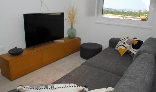 een woonkamer met een bank en een flatscreen-tv bij Vodice For You - Holiday Homes in Vodice