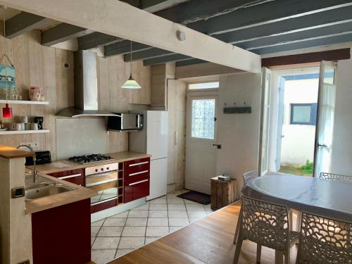 une cuisine avec un évier et une table avec des chaises dans l'établissement Les Marionnettes, Maison de ville 80m2 avec terrasse, à La Rochelle