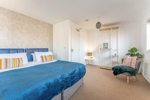 a bedroom with a blue bed and a chair at Newly Refurbished Townhouse, Free Parking & Garden in New Bilton