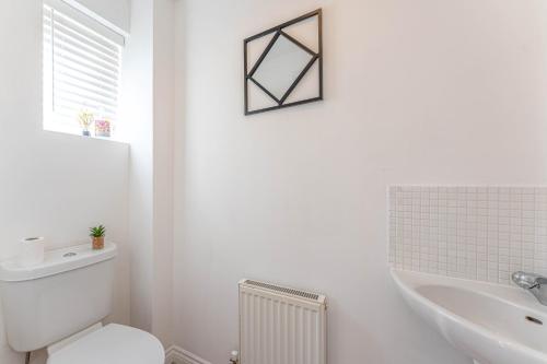 een witte badkamer met een toilet en een wastafel bij Newly Refurbished Townhouse, Free Parking & Garden in New Bilton
