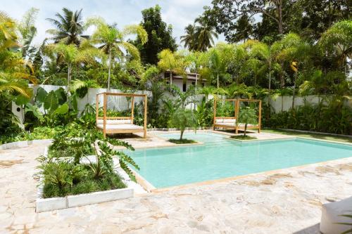a swimming pool with two benches in a garden at KALAVA VILLA in Ahangama