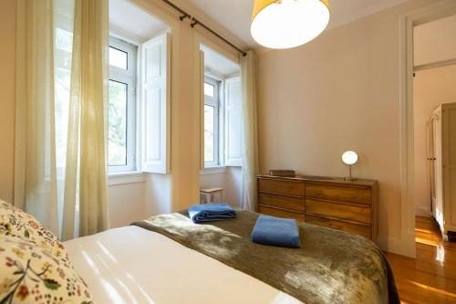 Schlafzimmer mit einem Bett, einer Kommode und Fenstern in der Unterkunft Ola Lisbon - Campo Pequeno in Lissabon