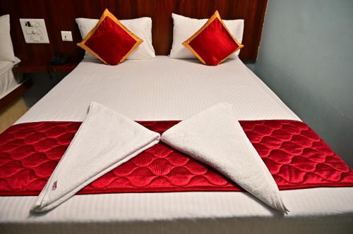 a large bed with red and white sheets and pillows at AMULYAM RESIDENCY in Narasingāpuram