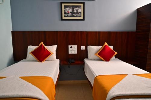 two beds in a hotel room with red and orange pillows at AMULYAM RESIDENCY in Narasingāpuram