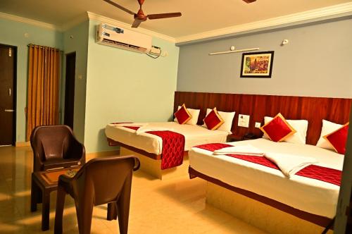 a hotel room with two beds and a chair at AMULYAM RESIDENCY in Narasingāpuram