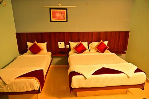 a hotel room with two beds with red pillows at AMULYAM RESIDENCY in Narasingāpuram