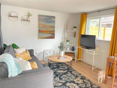 uma sala de estar com um sofá cinzento e uma televisão em NEW private tiny home near GreenLake/Lightrail/I-5 em Seattle