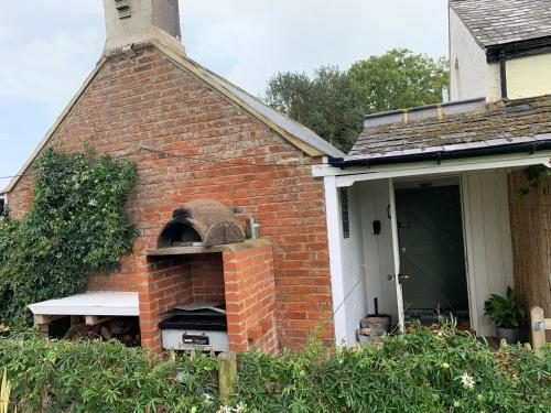 - un four en briques sur le côté d'une maison dans l'établissement Tiny Cottage for couples in the countryside, à Shalfleet