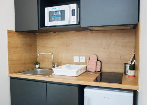 une cuisine avec un évier et un micro-ondes dans l'établissement Twenty Business Flats Béziers, à Béziers