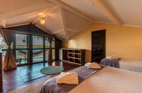 a bedroom with two beds and a large window at Barraca do Kite in Itarema