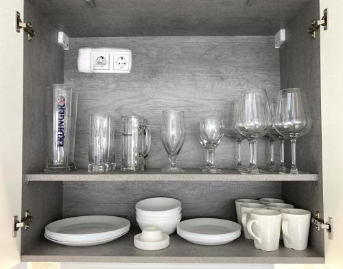 a shelf with wine glasses and plates and bowls at Living at Saarpartments -AdultsOnly- 2 Bedrooms, Kitchen- Business & Holiday Apartments for Long- and Short term Stay, 3 min to Train-Station, Secure E-Bike Parking! in Saarbrücken