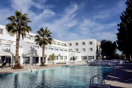 a hotel with a swimming pool in front of a building at Hotel Continental in Kairouan