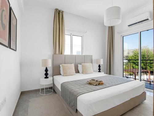 a white bedroom with a large bed and a window at Sanders White Mountains Pool Villas in Paphos City