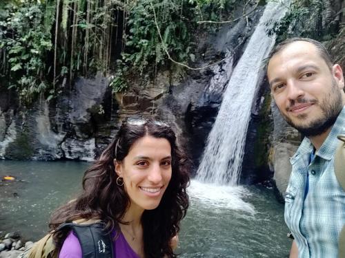 two people standing in front of a waterfall at FARILA LODGE in Kelimutu