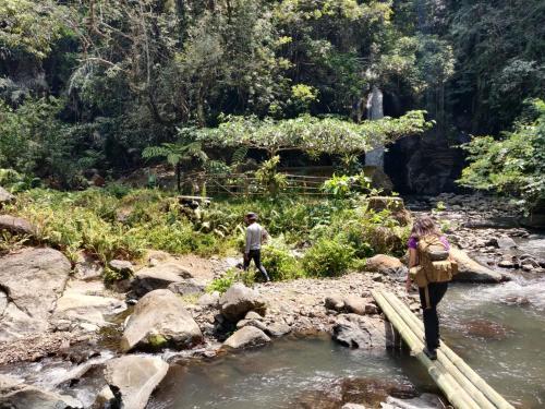 a man and a woman crossing a bridge over a river at FARILA LODGE in Kelimutu