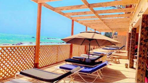a row of lounge chairs and an umbrella on a deck at Africa 6 Plage in Somone