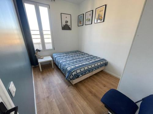 ein kleines Schlafzimmer mit einem Bett und einem Fenster in der Unterkunft En face du Stade de France in Saint-Denis