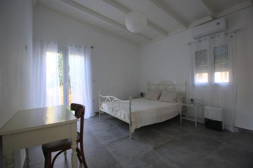 a white bedroom with a bed and a desk at Brand new house with garden, next to the beach in Áyios Ilías