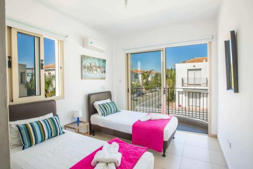a bedroom with two beds and a balcony at Villa Delia in Protaras