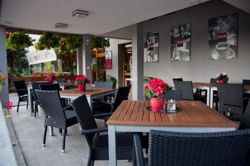 a restaurant with wooden tables and chairs and flowers at Motel Skalka in Radola