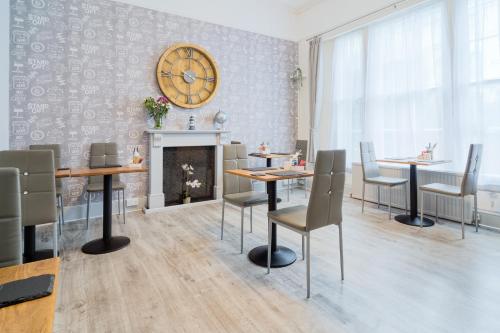 a dining room with tables and chairs and a clock on the wall at The Mariners - Torquay in Torquay