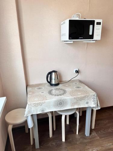 a table with a tea kettle on top of a microwave at Однокомнатная квартира в Жилгородке рядом с ДостарМед in Atyraū